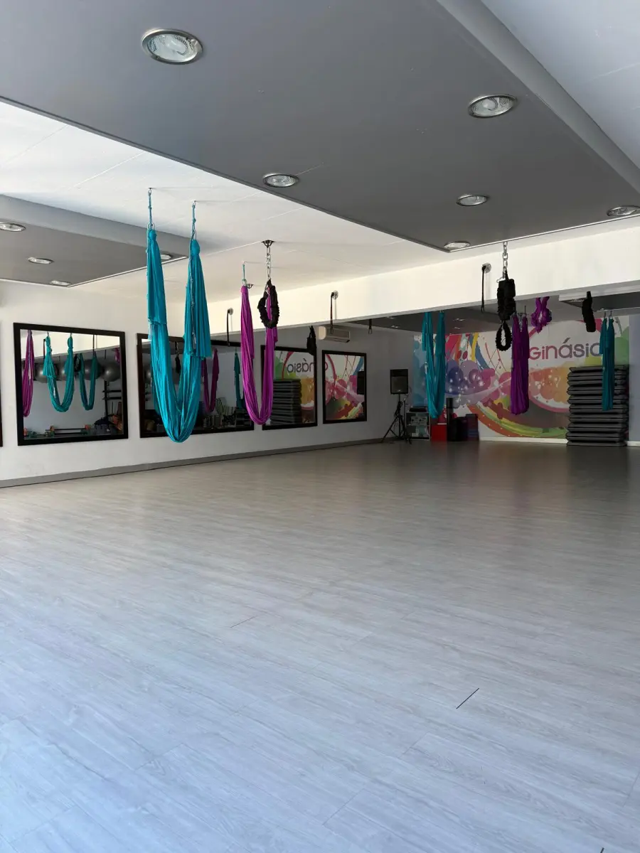 O Estúdio 2, amplo e vazio, com os tecidos de Aereo Yoga suspensos do tecto e o mural colorido ao fundo.