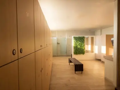 Balneários do Ginásio O2, com cacifos em madeira e uma parede verde.
