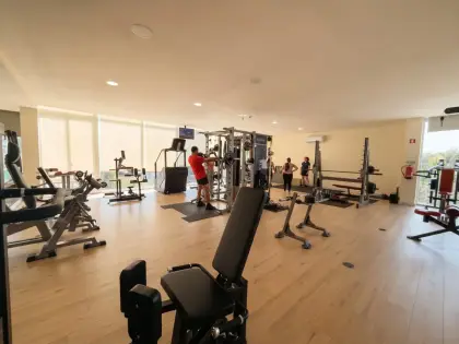 Alunos a treinar na sala de musculação, entre as máquinas e a zona de peso livre.